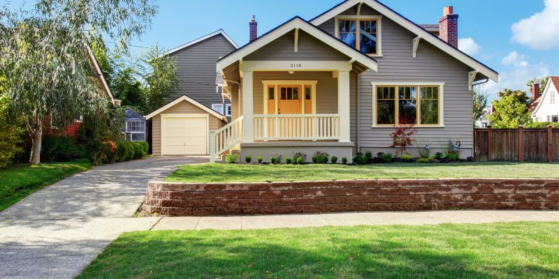 Grey house exterior with white porch and orange door House exterior with front yard landscape. White entrance porch with railings and orange entrance door